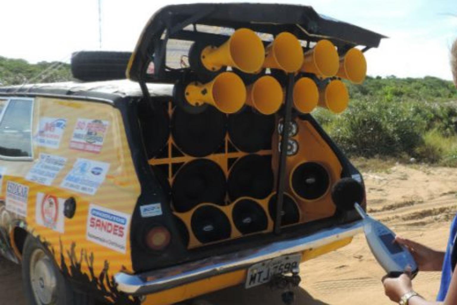 Carro amarelo com caixas de som sendo fiscalizado 