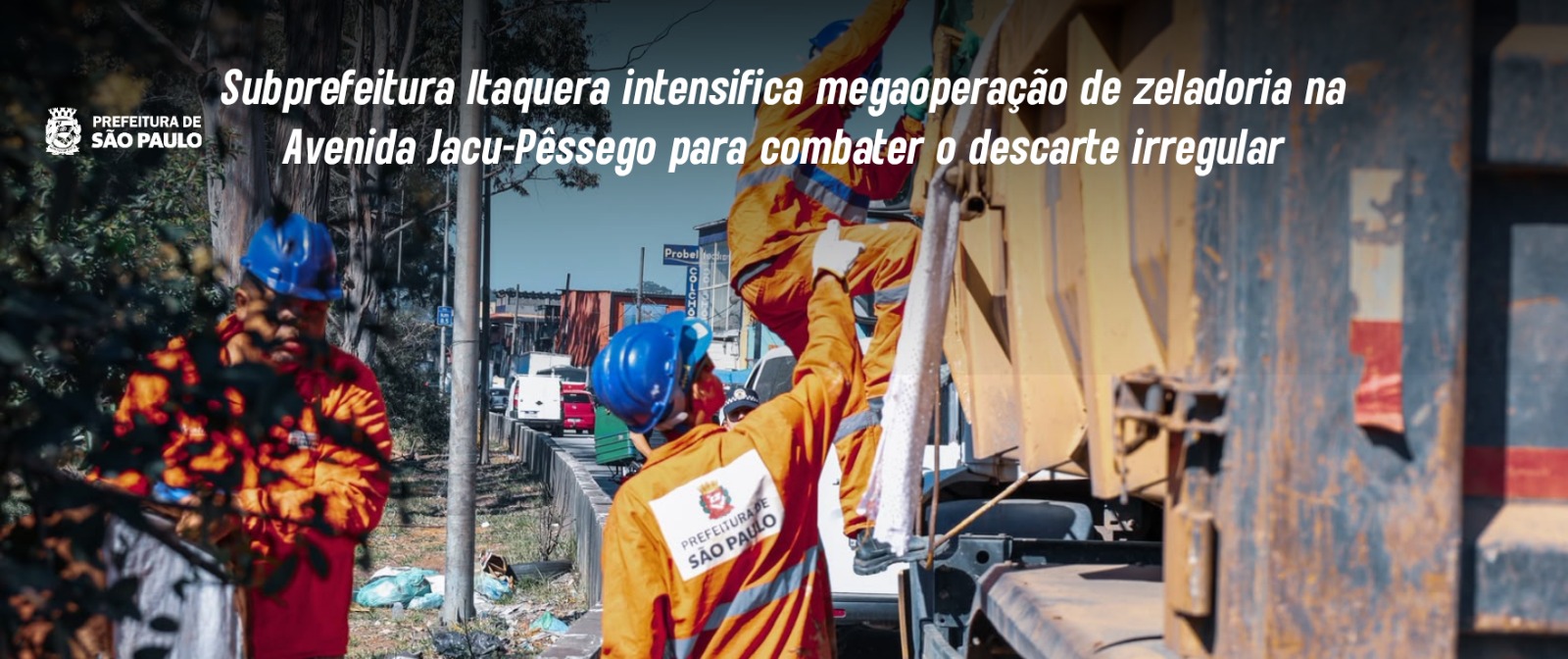 A imagem mostra trabalhadores de zeladoria urbana da Prefeitura de São Paulo em atividade na Avenida Jacu-Pêssego. Em primeiro plano, ao centro e à direita, um trabalhador veste uniforme laranja com o brasão e o nome 