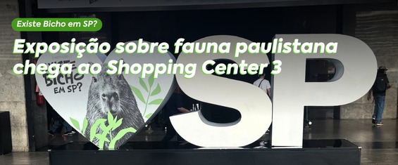 A imagem mostra uma foto de grande painel público com as letras “SP” em destaque, separadas por um coração central. Dentro do coração há a imagem de uma capivara acompanhada de ilustrações de plantas verdes. Sobre o coração, lê-se “Bicho em SP?”. Acima do painel, um banner verde traz a frase “Existe Bicho em SP?”. A composição visual combina elementos urbanos com a fauna local, chamando atenção para a biodiversidade presente na cidade e convidando o público a conhecer mais sobre os animais paulistanos.